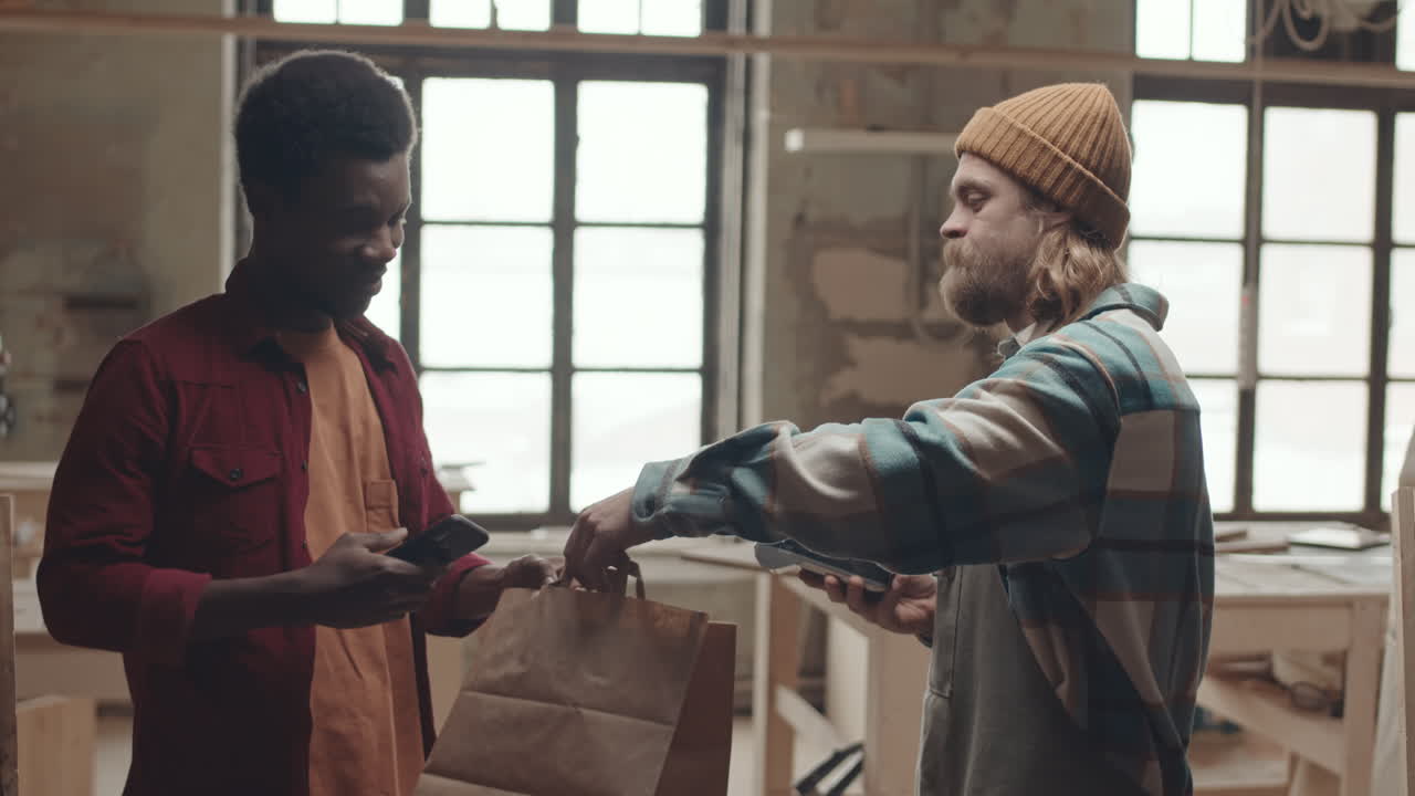 Male African American Customer Paying Joiner Using Smartphone