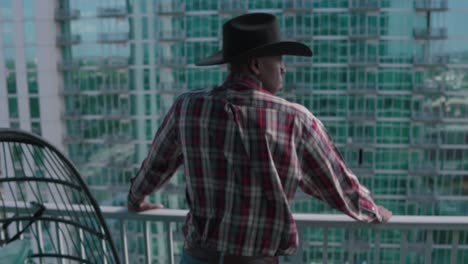 black man with black cowboy hat looking over balcony