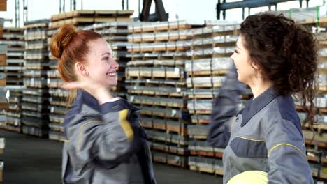 young happy female factory workers high fiving at the warehouse