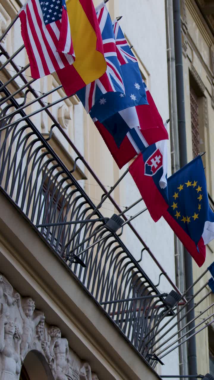 Multiple national and European flags wave on ornate embassy facade in Prague’s old town