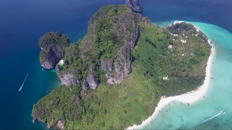 epic reversal drone shot over a mountainous tropical island surrounded by turquoise and navy blue water