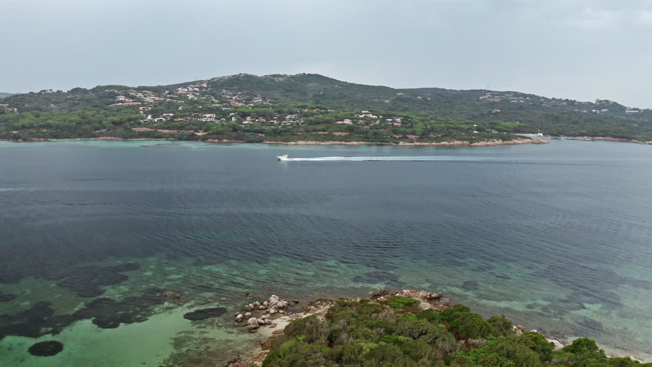Un motoscafo scivola sulle acque cristalline di una baia serena in Sardegna
