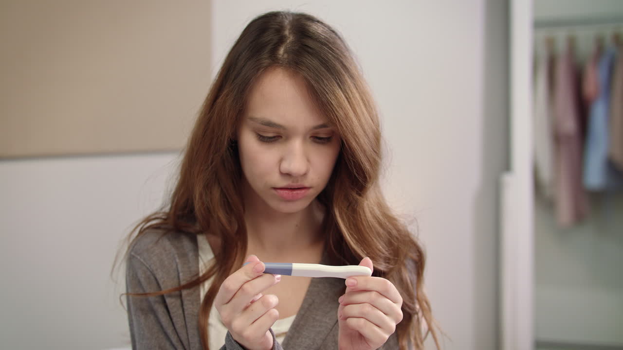 Worried woman waiting pregnant test results. Girl looking at pregnancy test