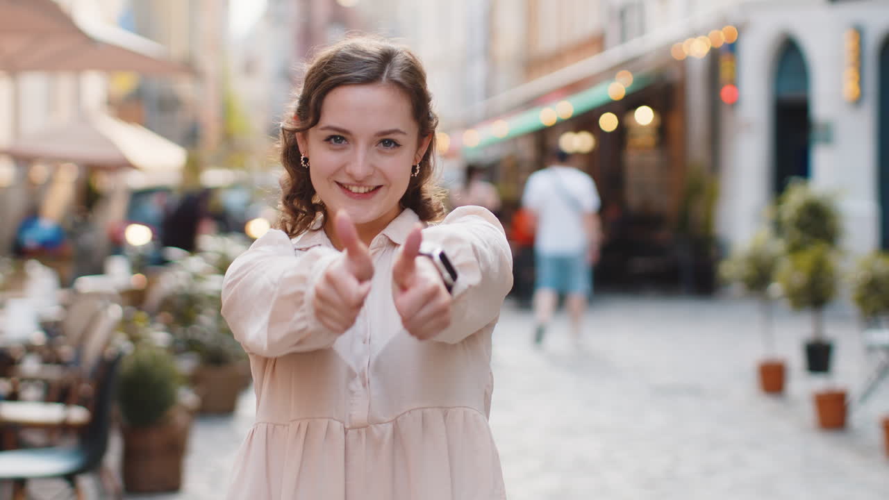 Young woman showing thumbs up like sign positive something good positive feedback in city street