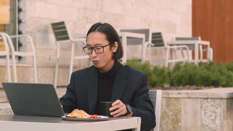 concentrated businessman working on laptop computer and drinking in a coffee shop at lunchtime