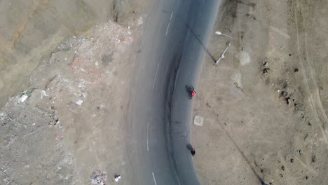 Drone-topdown-video-of-two-cyclists-going-up-a-hill-turn-on-their-bicycles