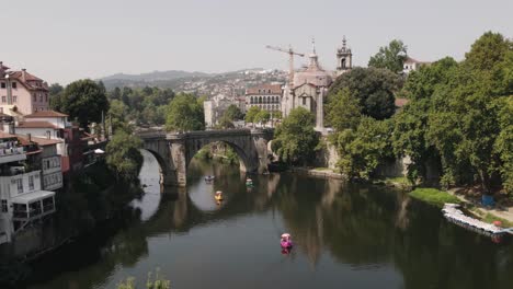 Bote-De-Remos-Cruzando-El-Río-Tamega-En-Un-Día-Tranquilo-Con-El-Puente-Sao-Goncalo-En-El-Fondo