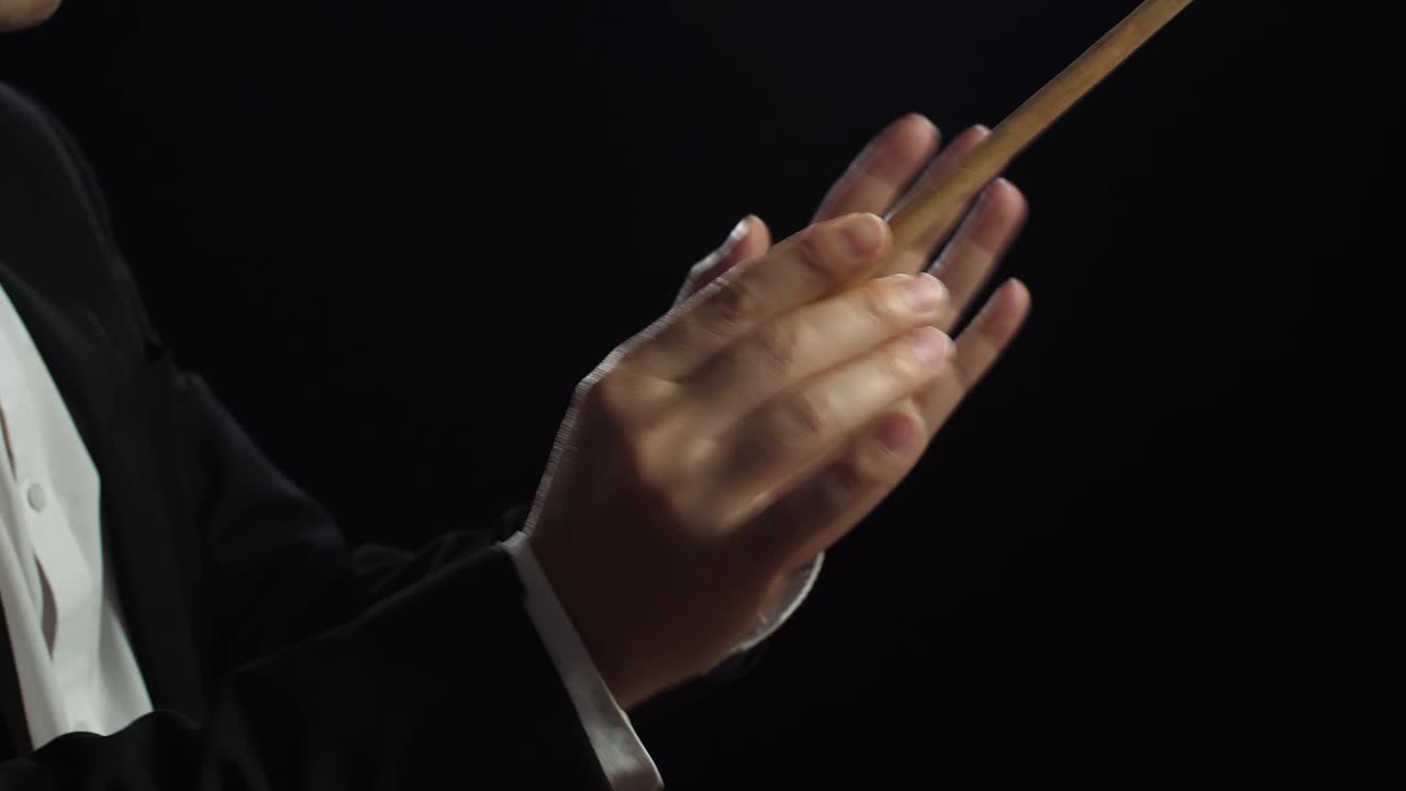 지휘자 손이 지이를 들고 검은 스튜디오에서 움직이는 근접한 측면 시각