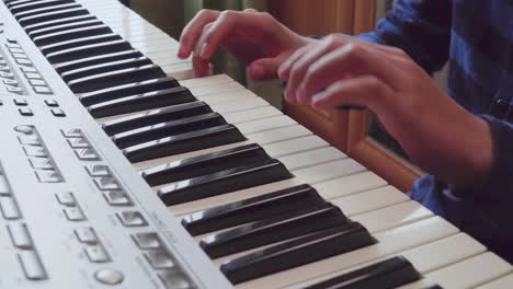 close-up of fingers of a boy learning playing the piano 01