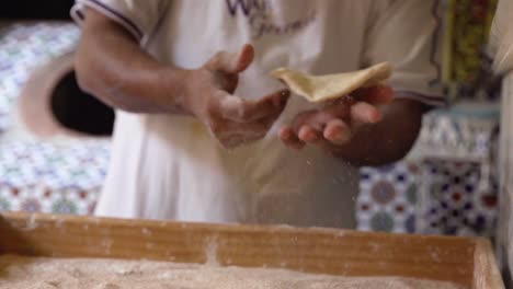 baker tossing dough in flour in bakery and putting bread in traditional oven