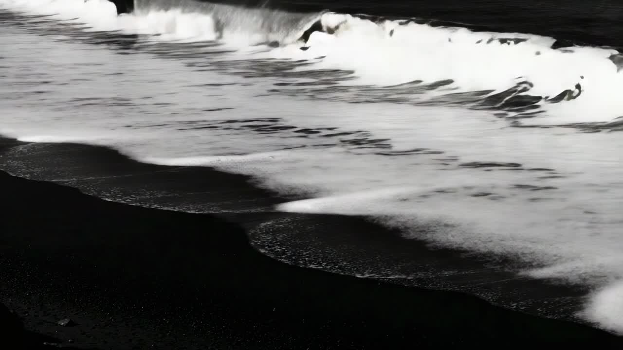 風に煽られたうねりが、黒い砂浜に沿って押し寄せ、波頭が立ち、砕け、泡とともに引いていく。