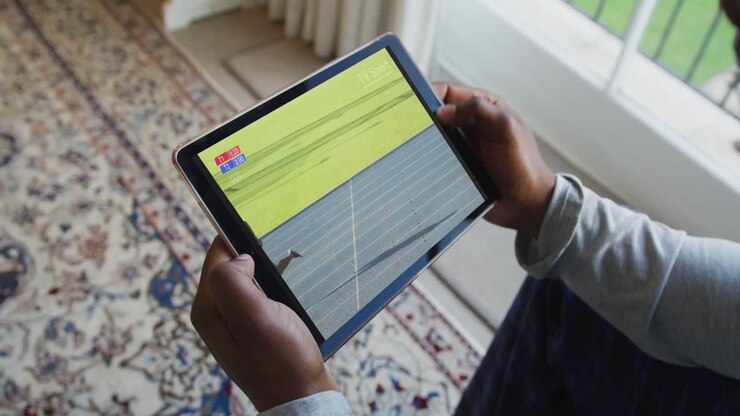 Composite of man sitting at home, watching athletics running event on tablet