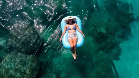 woman floating on an inflatable raft in clear tropical water