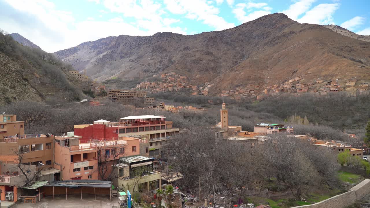 Warm sunlight bathes the terraced hills of Imlil Village, highlighting the earthy tones of traditional Berber houses