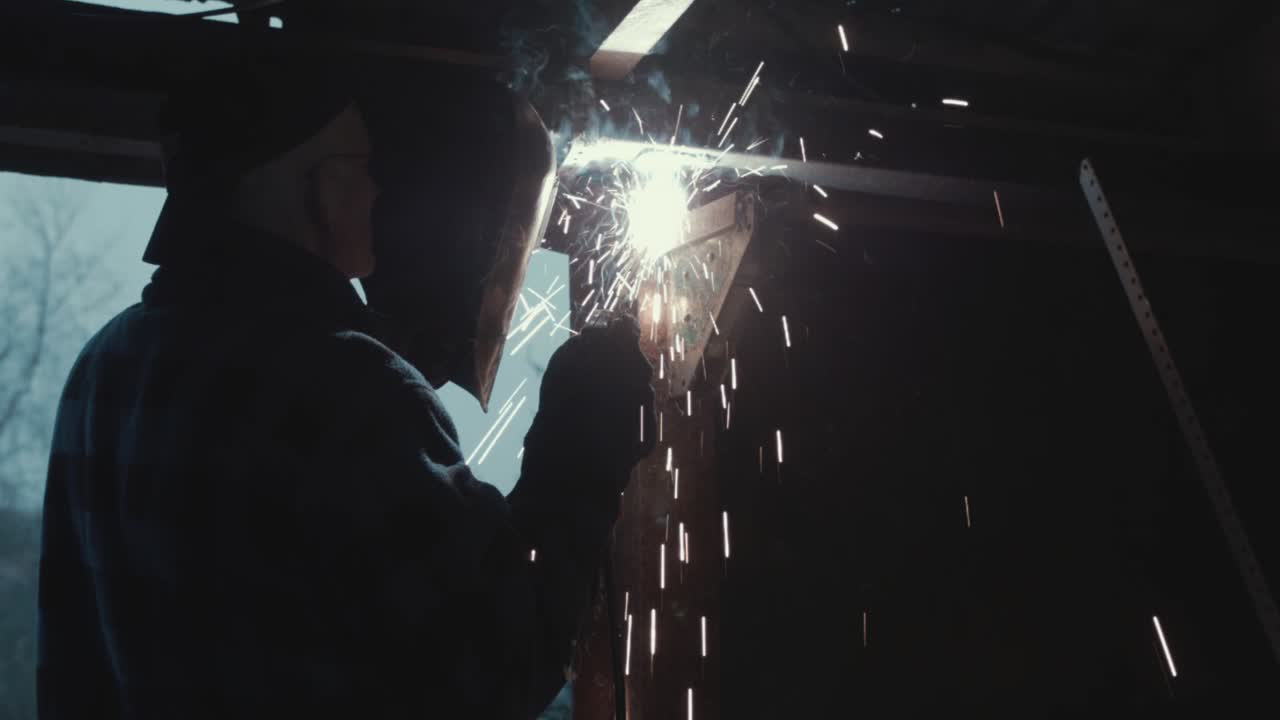 Stick welding mild steel metal in garage Medium shot
