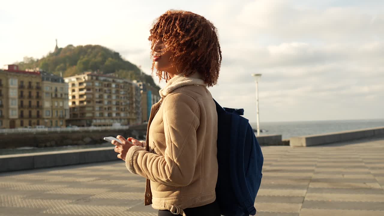 Woman with curly hair and backpack in an urban setting