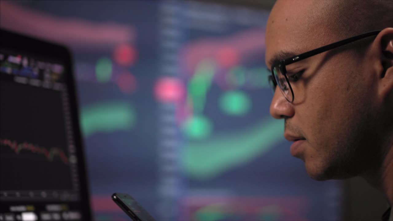 Financial analyst with exchange rate diagram on smartphone at night. Investor businessman analyzing a graphic of a stock, cryptocurrency exchange chart with cell phone. Investment concept