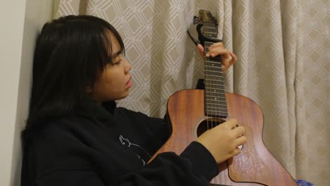 attractive filipino girl strumming acoustic guitar and jamming