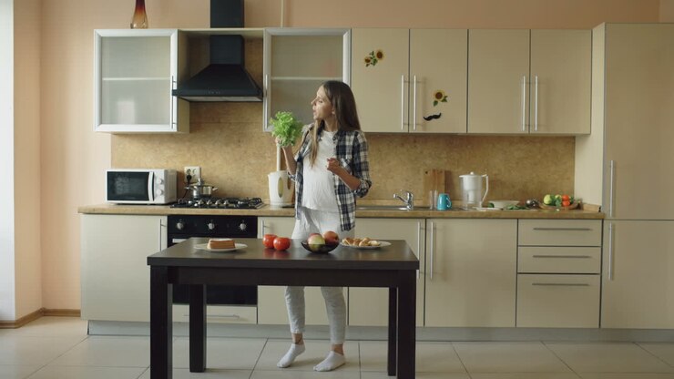 Ragazza e donna che ballano e mangiano in cucina