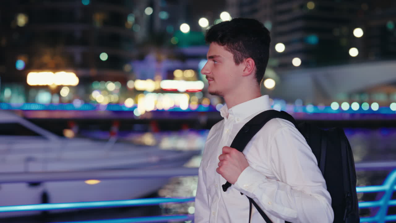 Man with backpack in the city at night