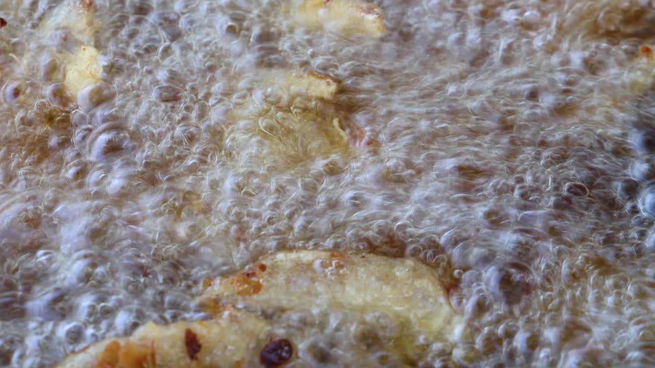 Golden potato fries frying in hot oil, intense bubbling, macro view, natural lighting, static camera