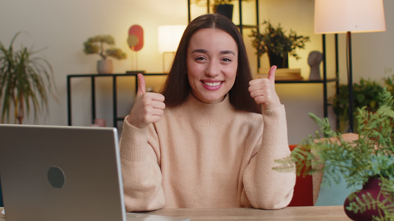 Happy caucasian young woman looking approvingly at camera show thumb up like positive sign good news