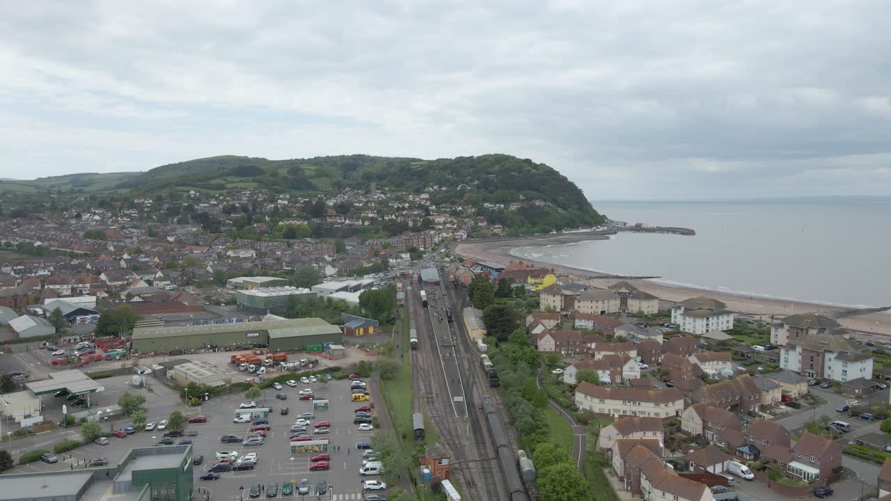 Aerial view of the Minehead steam railway station England's longest heritage line, running 20 miles between Minehead and Bishops Lydeard. Drone slowly moving downwards , with the hills in background