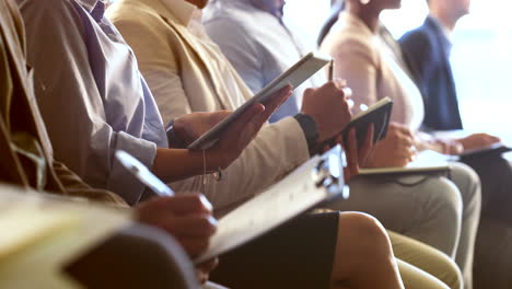 business people at a conference or meeting taking notes on tablets