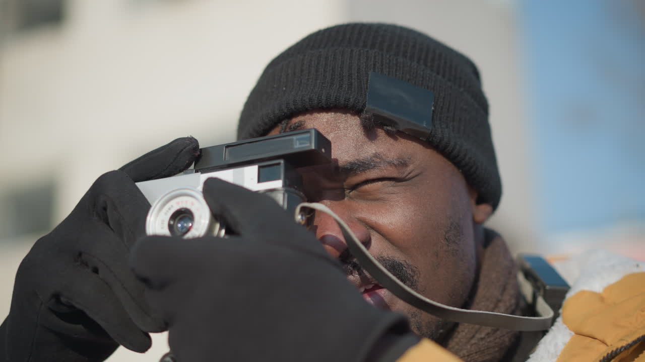 professional photographer eyes fixed on vintage camera adjusting lens ready shot under bright sunny sky with crisp light and blurred snowy urban background during busy winter stroll