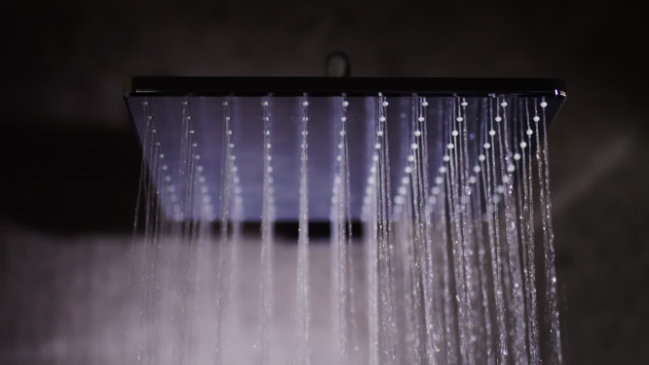 Proudy vody tečou ze čtvercové sprchové hlavice. Špičkové instalace a pohodlí, 4k zpomalené video