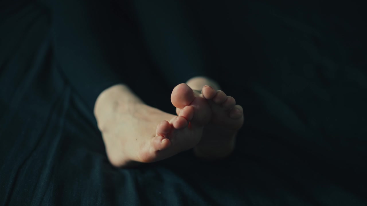 Primo piano di donna che muove le dita dei piedi mentre si rilassa sul letto