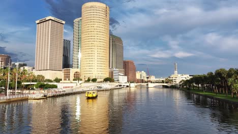 tampa skyline along the hillsborough river with a water taxi cruising by