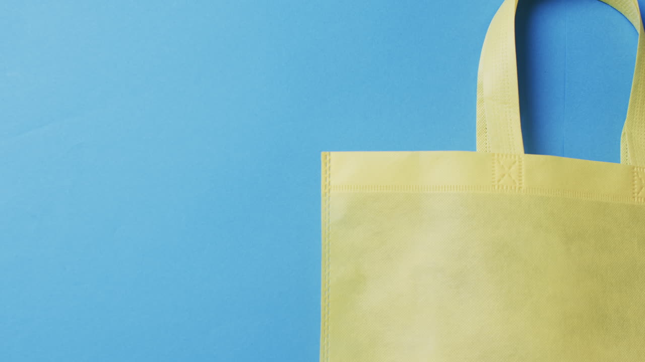 video de una bolsa de lona amarilla con espacio de copia en un fondo azul