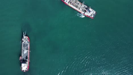 high drone view looking down at the environmental impact to a sensitive marine precinct cause by two large industrial ships maneuvering