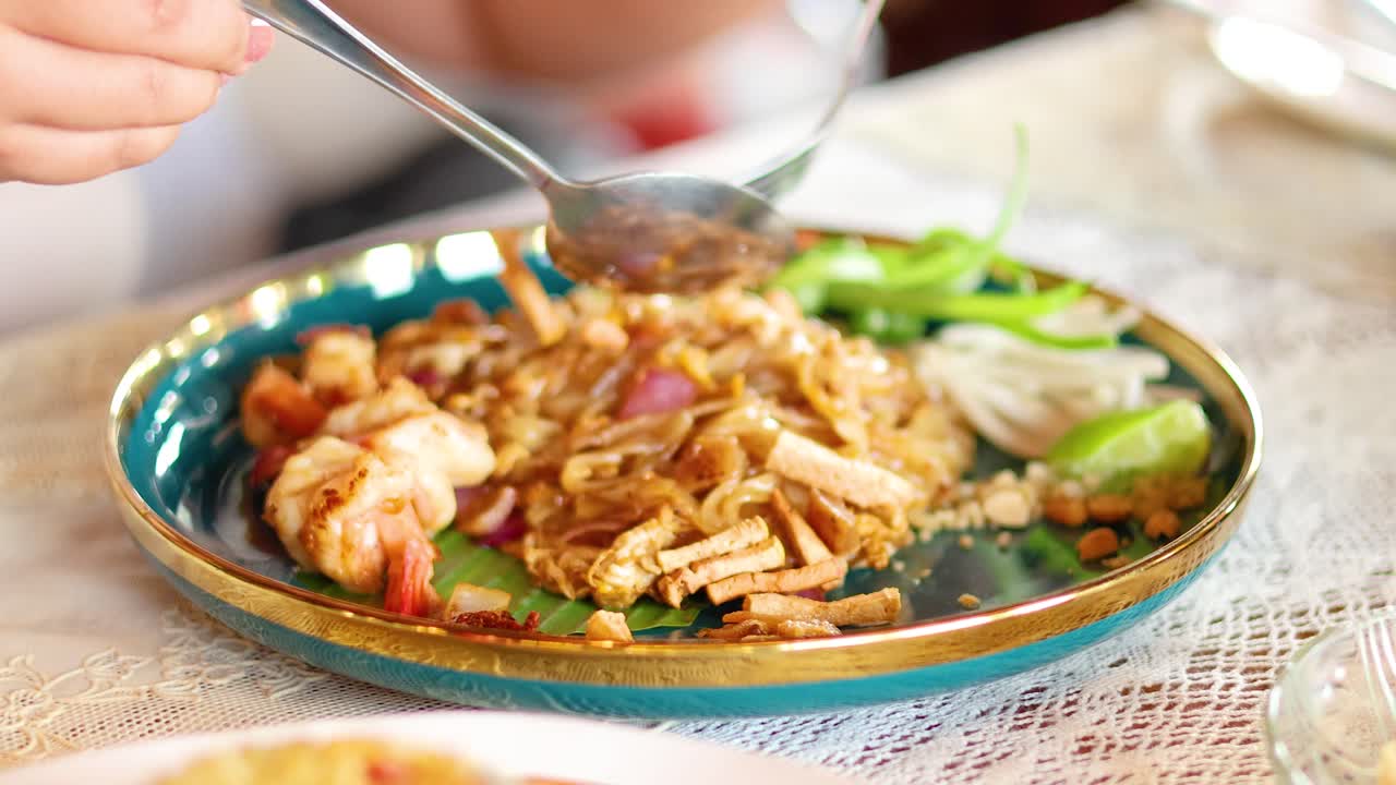 A person enjoys Pad Thai in a Bangkok restaurant, highlighting vibrant colors and traditional Thai cuisine