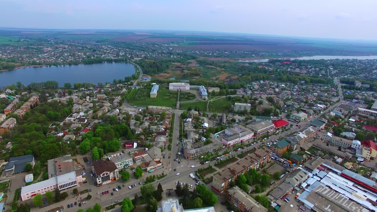 Little provincial city of Ukraine. Small pond and historical palaces in the centre. Agricultural fields at backdrop.