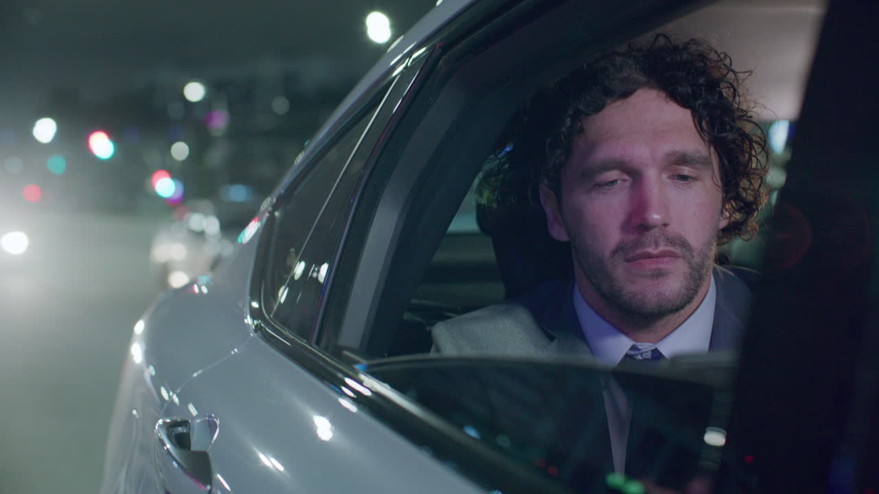 Businessman Using Smartphone during Car Ride in City at Night