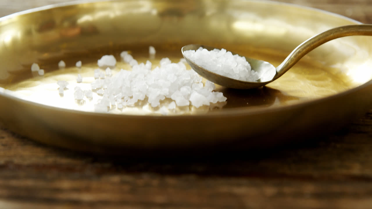 Salt in spoon and plate on wooden table 4k