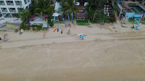 Surfistas-Con-Tablas-De-Surf-En-La-Playa-Tropical-De-Sanya,-China---Seguimiento-Aéreo