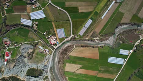 Agricultura-Ribereña:-Parcelas-E-Invernaderos-Que-Florecen-A-Lo-Largo-De-Las-Orillas-De-Un-Río-Sereno-En-Un-Impresionante-Valle-Rural-En-Primavera,-Albania