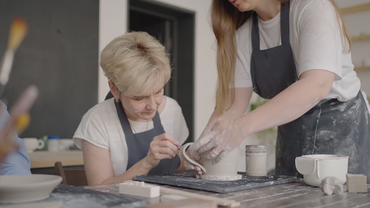 Three elderly people work on a potter's wheel in slow motion