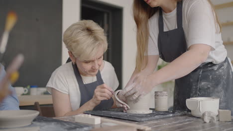 Three-elderly-people-work-on-a-potter's-wheel-in-slow-motion