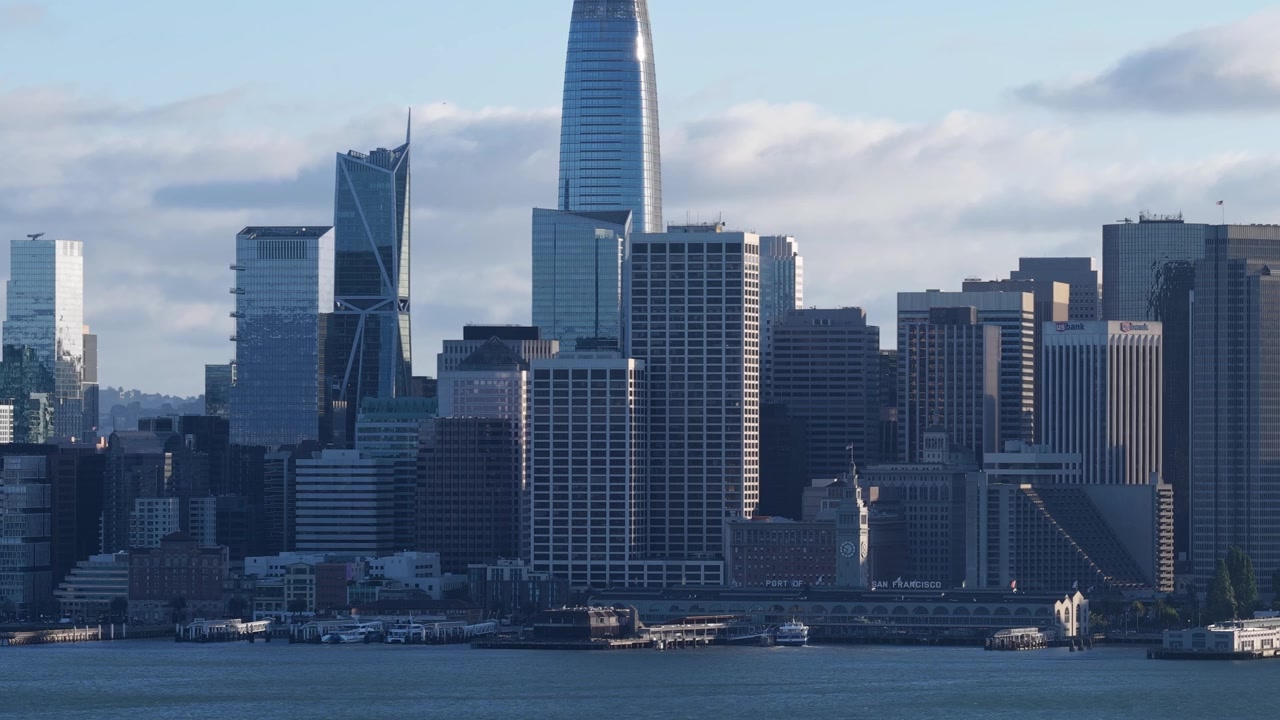 Vista aerea in ascesa con drone dello skyline del centro di San Francisco, con grattacieli del quartiere finanziario e riflessi della luce serale, vista dall'altra parte della ba baia