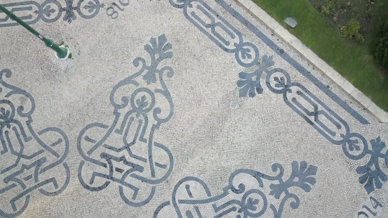 In the early hours before the World Youth Days, an aerial view showcases Lisbon's streets adorned with its iconic patterned mosaic sidewalks, a picturesque scene anticipating the day's events