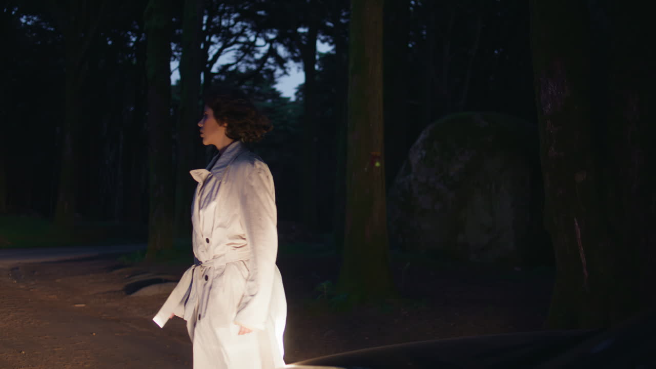 밤의 숲길에서 자동차 헤드라이트를 비추는 여자. 여자가 생각나는 여행