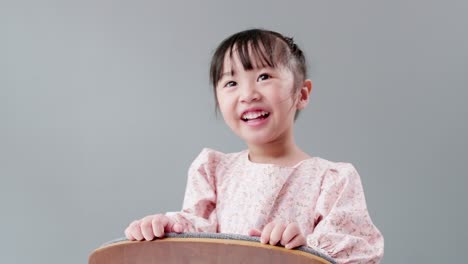 Child-emerging-behind-chair,-playing-to-hide-and-looking-at-camera