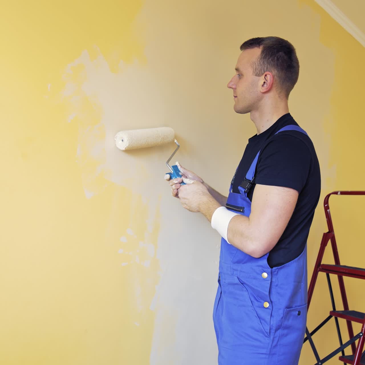 Young worker painting wall in room. Offering professional painting services