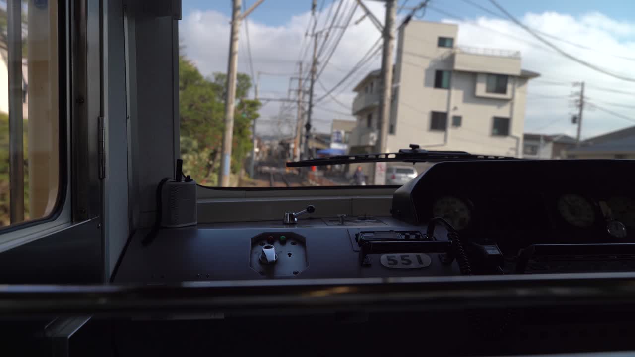 View Of Buildings And Green Trees Inside The Cabin Of A Train Driving On The Railway Of Enoshima Dentetsu Line In A Japanese Town In Japan - Wide Shot
