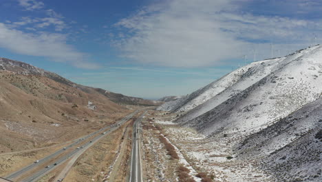 aerial lowering shot, california highway by snowy mountains on winter day