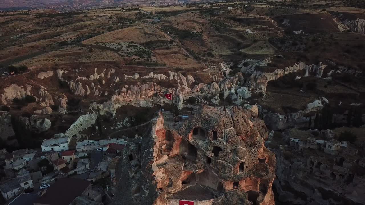 Cappadocia, Aerial View of Mountain Ortahisar Castle With Caves And Turkish National Flag Under Sunset Sunlight